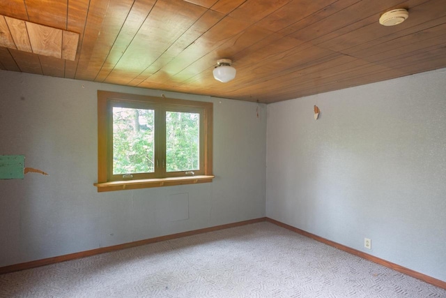 spare room featuring wood ceiling and light colored carpet