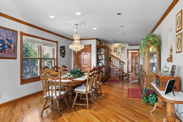 dining space featuring light wood-type flooring, ornamental molding, and a chandelier