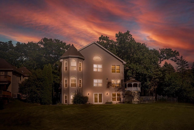 back house at dusk featuring a yard