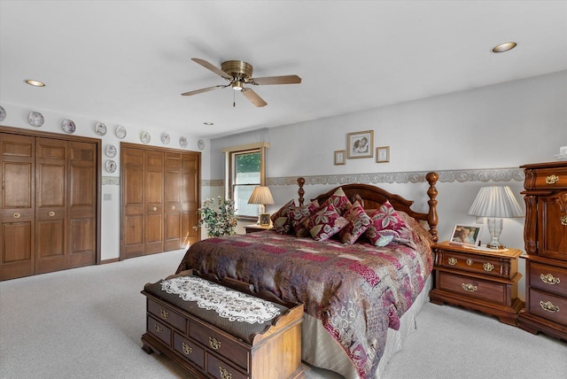 carpeted bedroom with ceiling fan and two closets