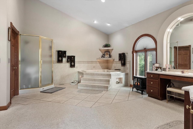 bathroom with tile flooring, independent shower and bath, vanity, and lofted ceiling