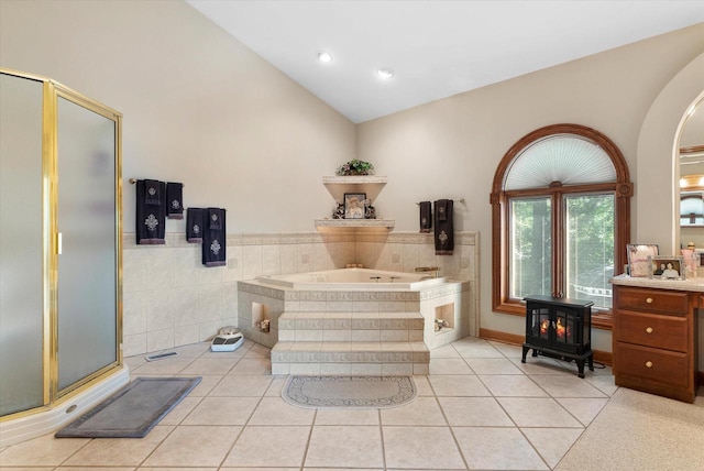 bathroom with separate shower and tub, a wood stove, vanity, and vaulted ceiling