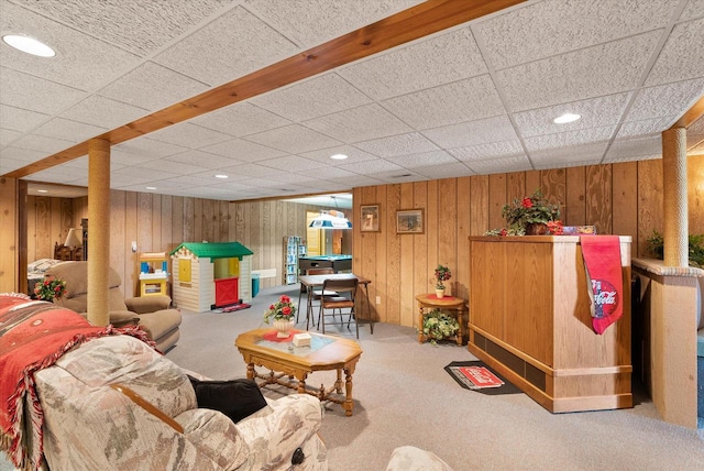 interior space featuring a paneled ceiling, light carpet, and wooden walls