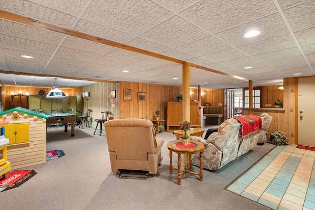 carpeted living room with wooden walls, billiards, and a drop ceiling