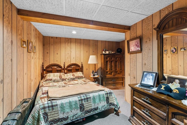 bedroom featuring light carpet, a drop ceiling, and wood walls