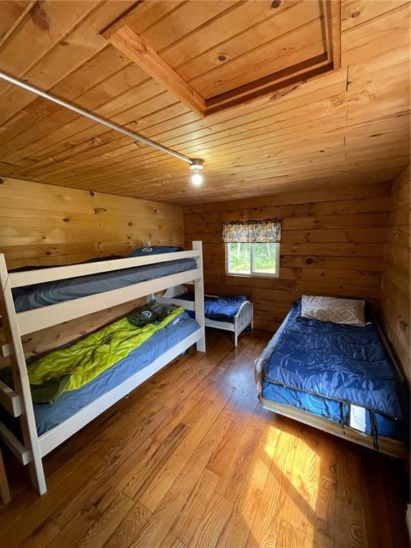 N2141 Pondell Ln, Bruce, WI 54819 - unfurnished bedroom featuring billiards, wood walls, wood ceiling, and hardwood / wood-style flooring