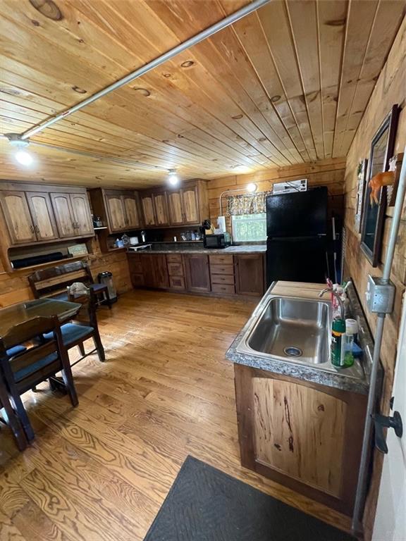 N2141 Pondell Ln, Bruce, WI 54819 - kitchen featuring wooden walls, sink, wood ceiling, light hardwood / wood-style flooring, and black appliances