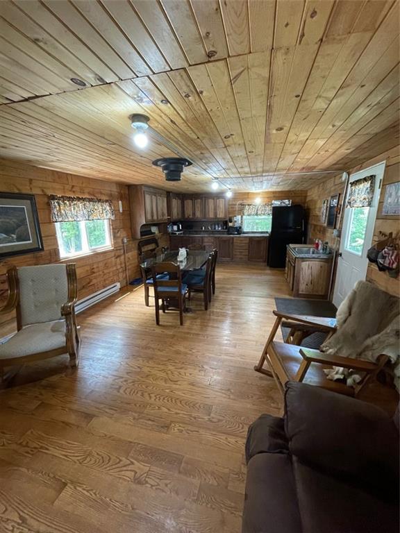 N2141 Pondell Ln, Bruce, WI 54819 - living room with plenty of natural light, wooden walls, wooden ceiling, and hardwood / wood-style flooring