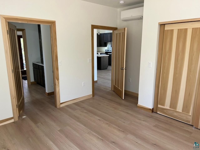 unfurnished bedroom with a wall mounted AC, a closet, and wood-type flooring