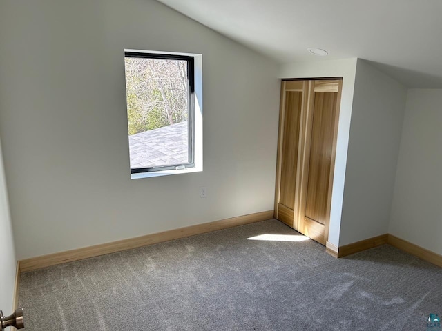 unfurnished bedroom with a closet, vaulted ceiling, and carpet flooring