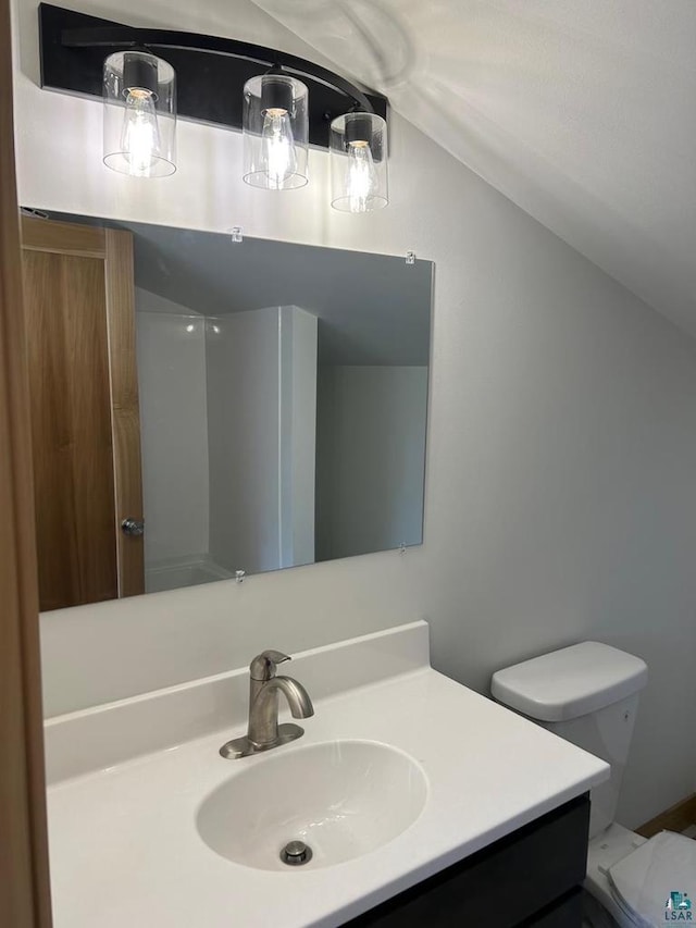 bathroom featuring vanity, toilet, and lofted ceiling