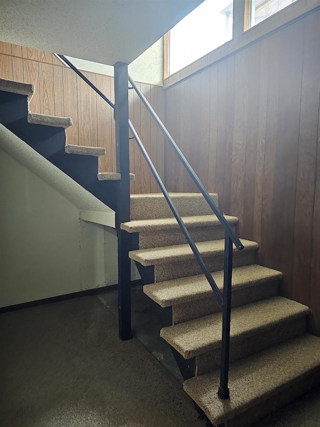 stairway featuring wood walls