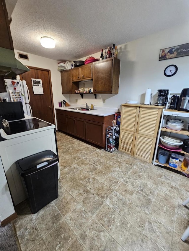 kitchen featuring sink, light tile floors, a textured ceiling, dark brown cabinets, and white refrigerator