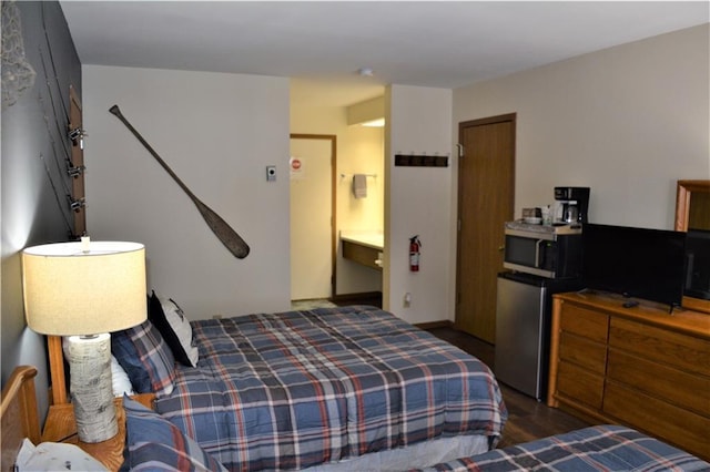 bedroom with connected bathroom, refrigerator, and dark hardwood / wood-style flooring