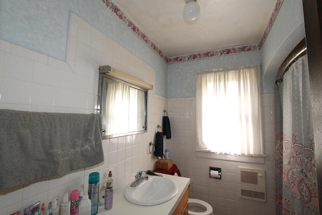 bathroom with vanity, a healthy amount of sunlight, and tile walls