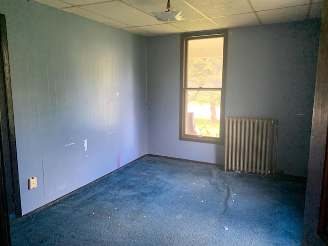 carpeted empty room with a drop ceiling and radiator