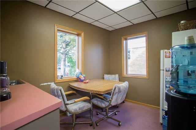 carpeted dining area with a drop ceiling