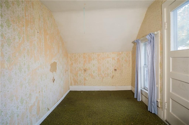 additional living space featuring dark colored carpet and vaulted ceiling