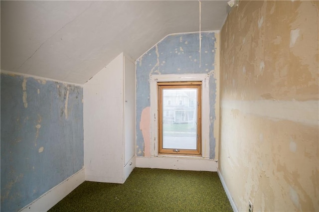 bonus room with lofted ceiling and dark colored carpet