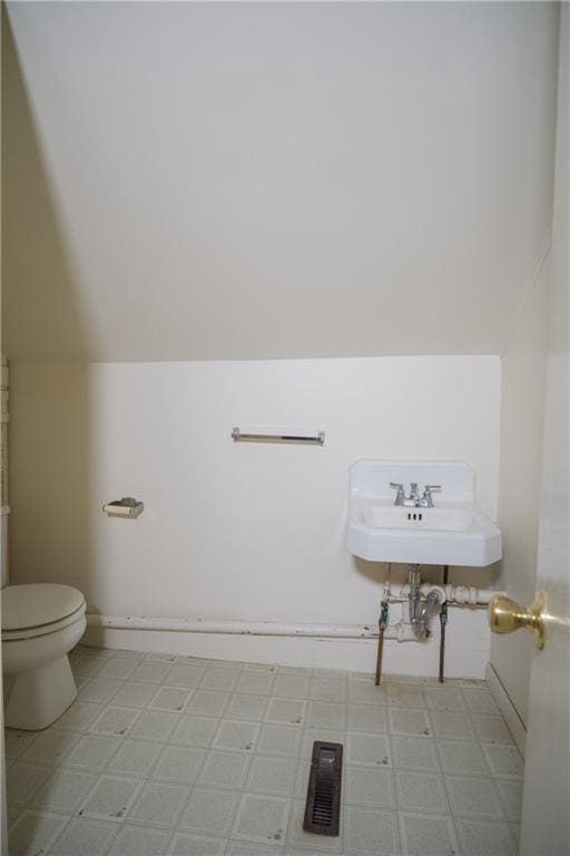 bathroom featuring sink, toilet, tile floors, and vaulted ceiling