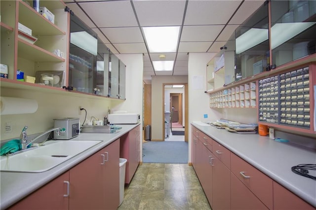 kitchen with sink, light tile floors, and a paneled ceiling