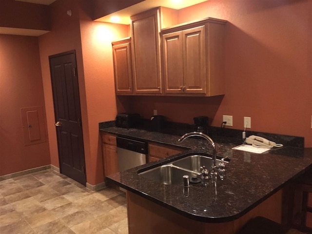 kitchen with stainless steel dishwasher, light tile floors, dark stone counters, kitchen peninsula, and sink