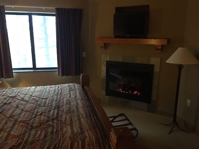 bedroom with a tile fireplace, carpet flooring, and multiple windows