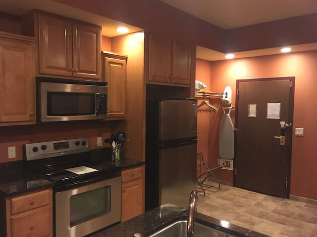 kitchen featuring light tile floors, dark stone counters, and stainless steel appliances