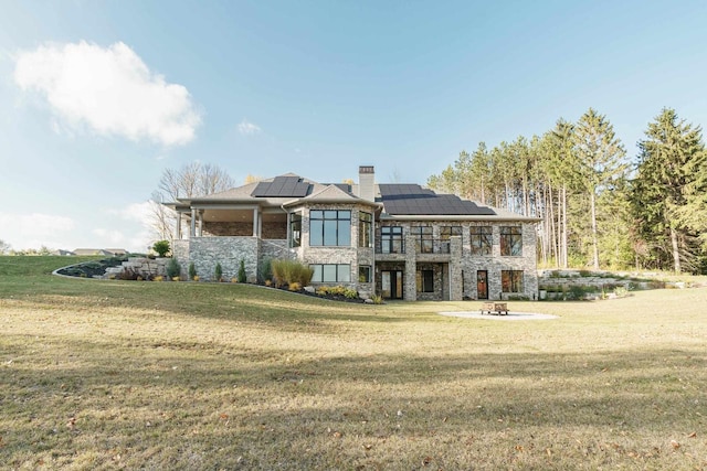 back of property featuring a lawn and solar panels