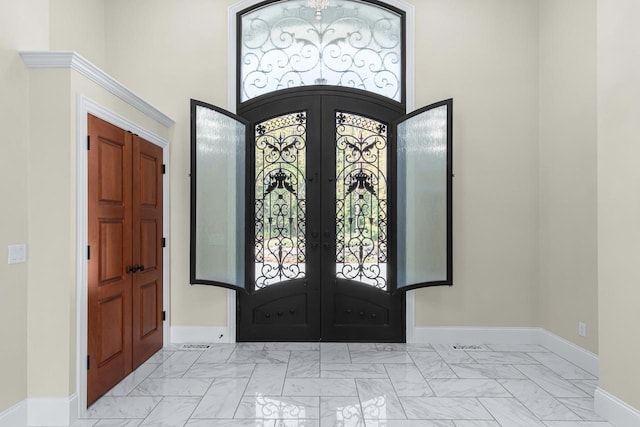 foyer featuring light tile floors, french doors, and a high ceiling