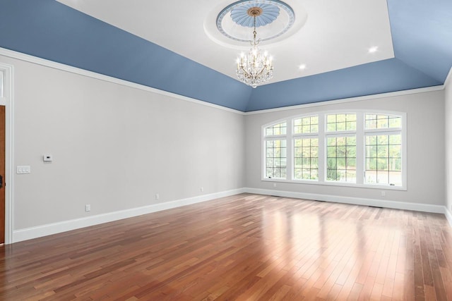 spare room with vaulted ceiling, wood-type flooring, and an inviting chandelier