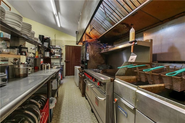 kitchen featuring luxury range, light tile floors, dark brown cabinets, stainless steel counters, and lofted ceiling