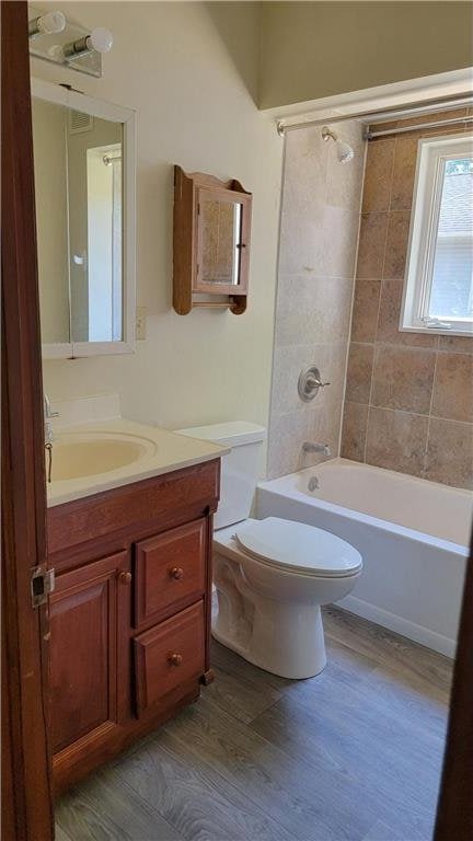 full bathroom featuring tiled shower / bath combo, toilet, vanity, and wood-type flooring