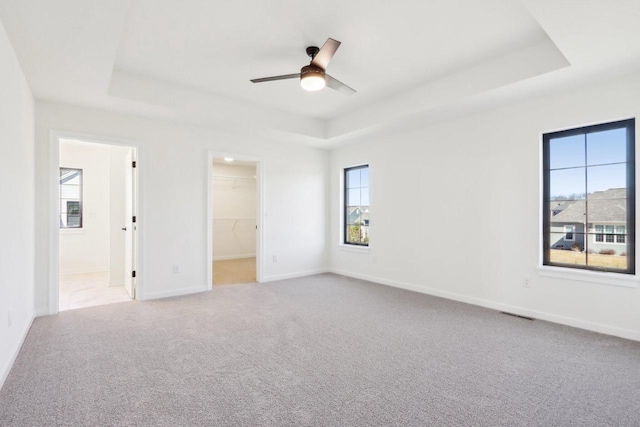 spare room with baseboards, carpet flooring, a ceiling fan, and a tray ceiling