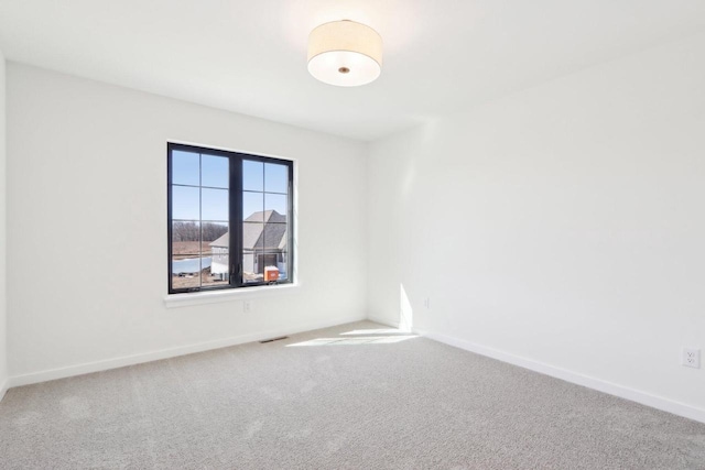 carpeted spare room featuring visible vents and baseboards