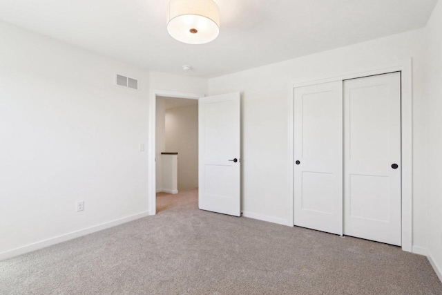 unfurnished bedroom with carpet, visible vents, a closet, and baseboards