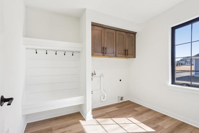 clothes washing area with cabinet space, baseboards, light wood finished floors, and electric dryer hookup