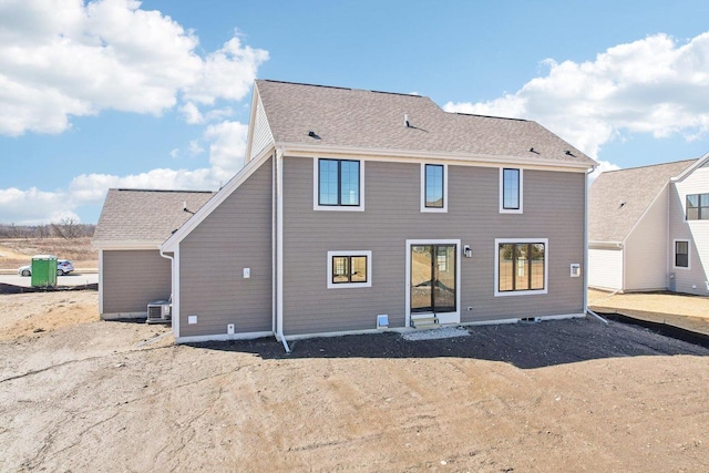 back of property with a shingled roof and central AC