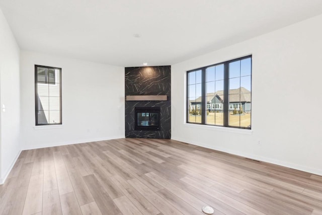 unfurnished living room featuring visible vents, a fireplace, baseboards, and wood finished floors