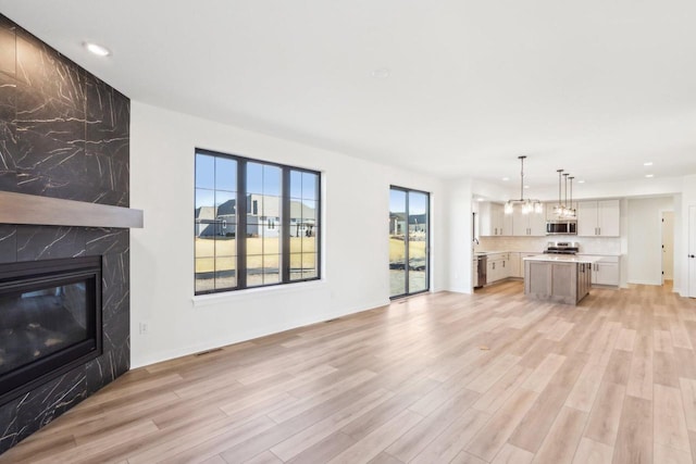 unfurnished living room featuring visible vents, recessed lighting, light wood-style floors, and a premium fireplace