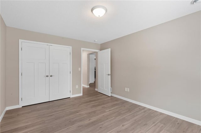 unfurnished bedroom with a closet and light wood-type flooring