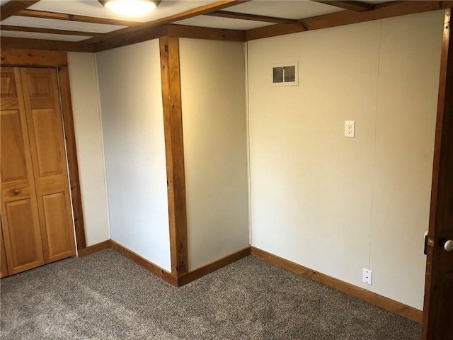 unfurnished bedroom featuring beam ceiling and dark colored carpet