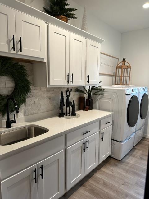 washroom featuring light hardwood / wood-style flooring, sink, cabinets, and independent washer and dryer