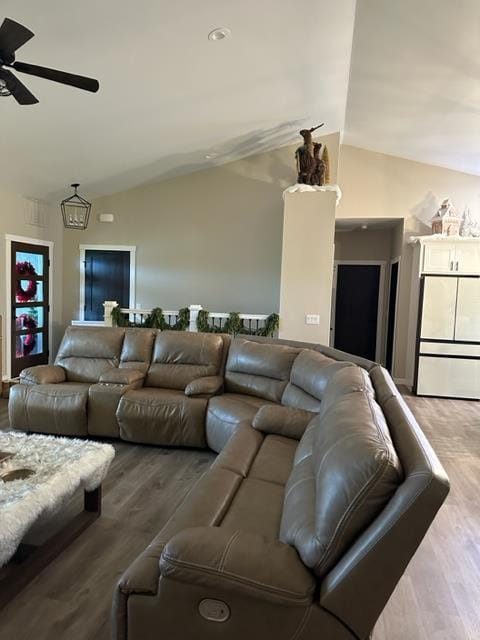 living room with ceiling fan, wood-type flooring, and vaulted ceiling