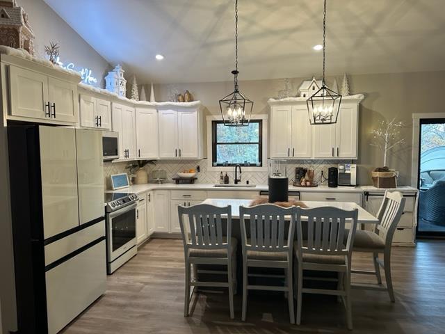 kitchen featuring dark hardwood / wood-style floors, a kitchen island, appliances with stainless steel finishes, a chandelier, and decorative light fixtures