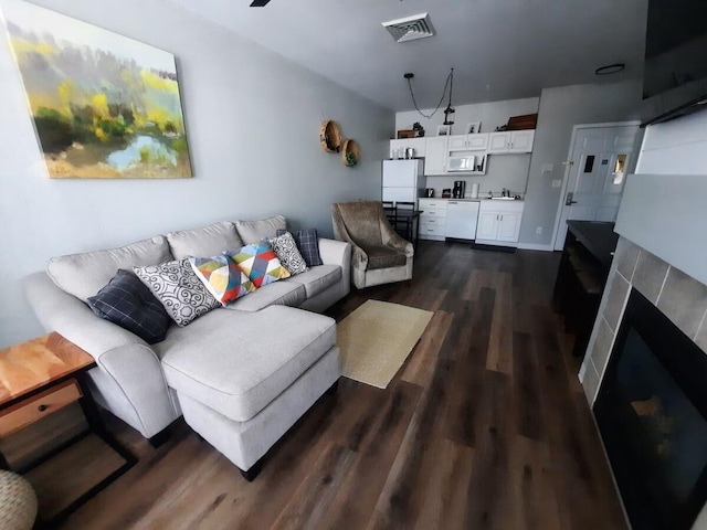 living room with dark hardwood / wood-style flooring and a tile fireplace