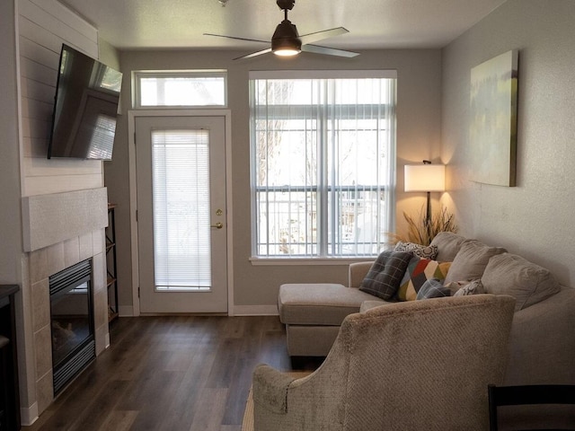 living room featuring a fireplace, ceiling fan, and dark wood-type flooring