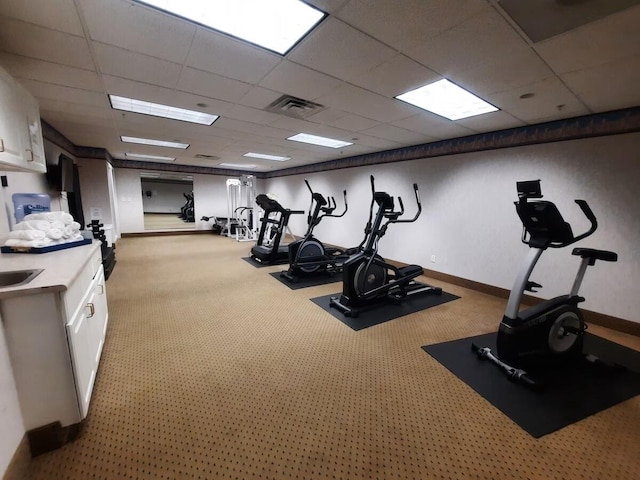 gym with a paneled ceiling and light carpet