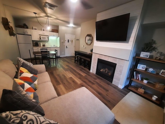 living room with sink, dark wood-type flooring, and a tile fireplace