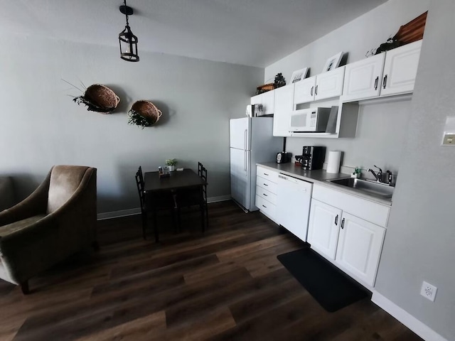 kitchen featuring pendant lighting, white appliances, sink, dark hardwood / wood-style flooring, and white cabinetry